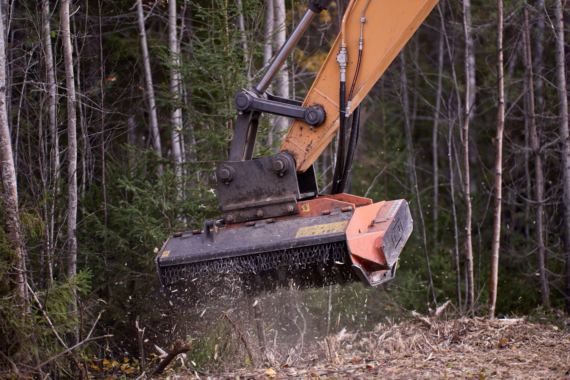 Mulching attachment on excavator, being used to clear roadside brush.